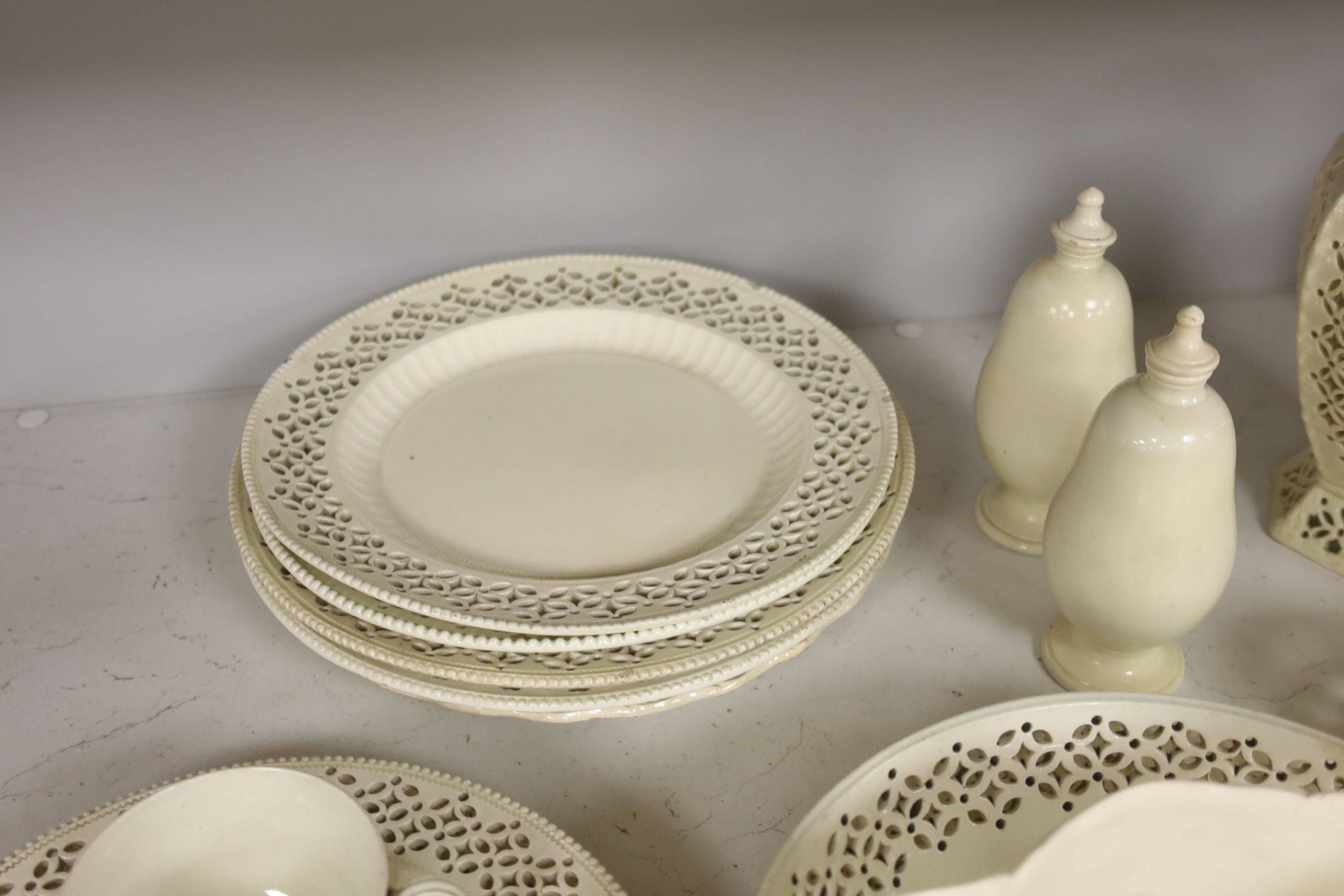 A collection of creamware, circa 1800, Staffordshire and Yorkshire comprising three pairs of plates, with moulded laurel swags, pair of small bottle coasters, sauceboat, saucer dish, two teacups, cruet stand, two pear sh